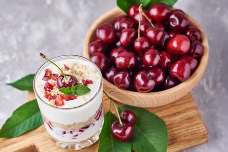 Smoothie with summer cherry in glass jar and fresh berries  in wooden bowl on gray backgroundの写真素材