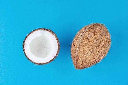 Full coconut and cracked half on blue background, top view