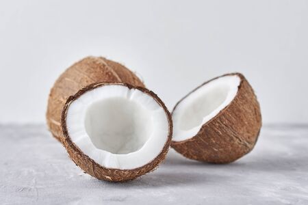 Full Coconut and cracked half on white background, close up