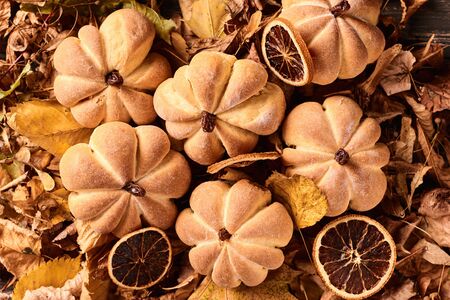 Homemade cookies in shape of pumpkin in autumn leaves. Halloween handmade cookies on table, close upの写真素材