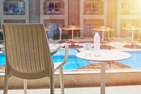 Glass of water and plastic bottle on balcony against swimming pool backgroundの写真素材