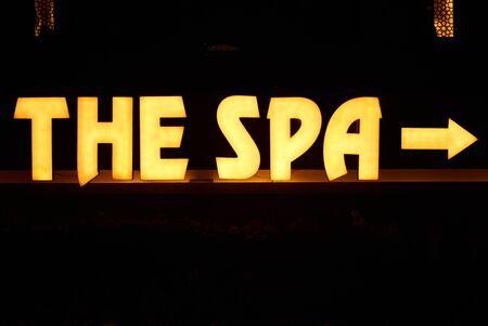 Glowing spa inscription with luminous letters and arrow pointer on dark backgroundの写真素材