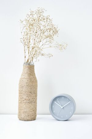 Classic alarm clock and flower branch in vase, minimal style background