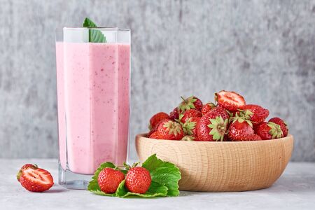 Strawberry smoothie in glass jar and fresh strawberries in wooden bowl on gray background. Healthy breakfastの写真素材