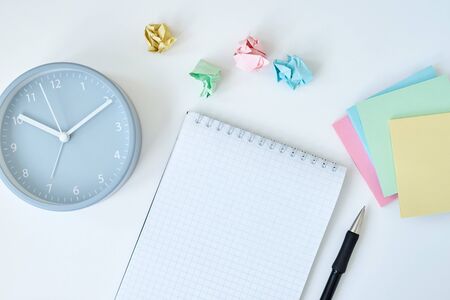Gray round alarm clock colorful sticky notes and notebook on white background, top viewの写真素材