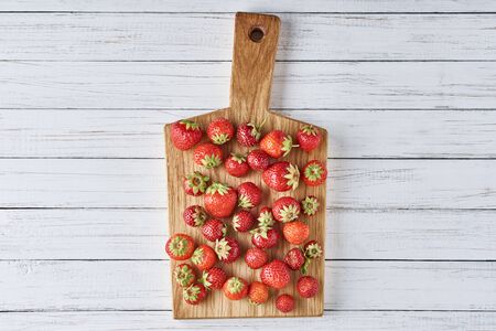 Heap of fresh strawberries with cutting board on gray background, top view. Healthy nutritionの写真素材