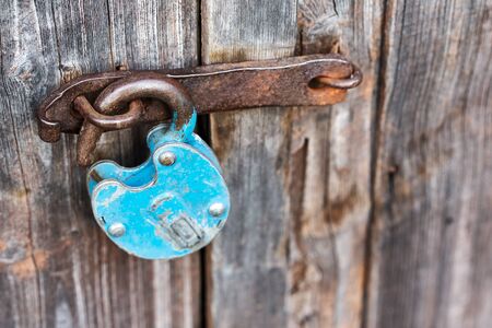 Blue old rusty unlocked padlock on a wooden doorの写真素材
