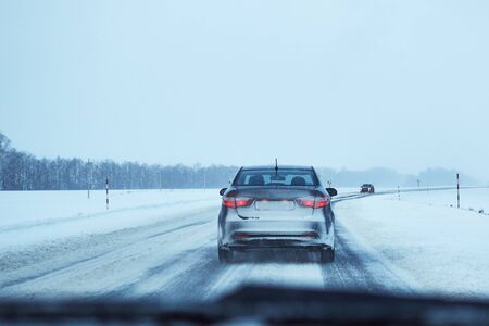 Back view of car on a snowy winter roadの写真素材