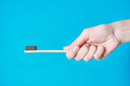Wooden eco friendly bamboo toothbrush on blue background. Dental care conept