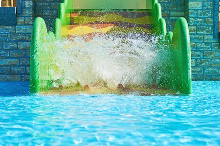 Woman and two boys on water park slides. Happy family ride on water slides with flowing splash in aqua parkの写真素材