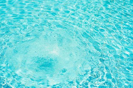 Background of water in blue swimming pool, water surface with sun reflection