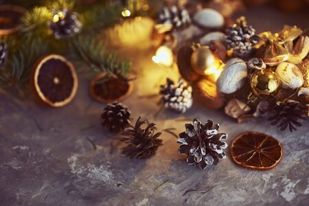 Christmas decorations with garland lights, pine cones and fir tree branch on dark backgroundの写真素材