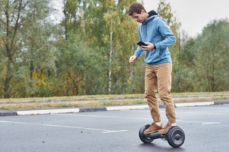 Man riding on hoverboard and using smartphone outdoorの写真素材