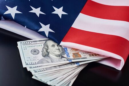USA national flag and dollar bills on dark background. Business and finance conceptの写真素材