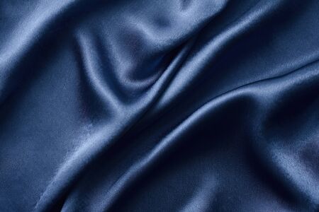 Silver silk background with folds.  Abstract texture of rippled silk surfaceの写真素材