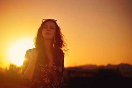 young curly woman silhouette walking outdoor at sunsetの写真素材