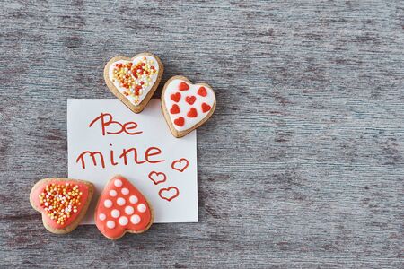 Deocrated heart shape cookies and paper sheet with inscription be mine on gray background. Valentines Day conceptの写真素材