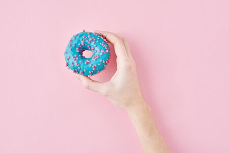 Woman hand take color donut on pink background. Creativity minimalism style food concept, top viewの写真素材