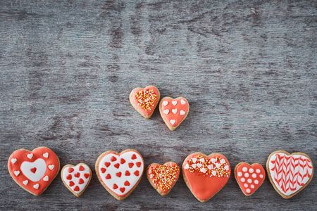Background of decorated with icing and glazed heart shape cookies on gray background, flat lay. Valentines Day food conceptの写真素材