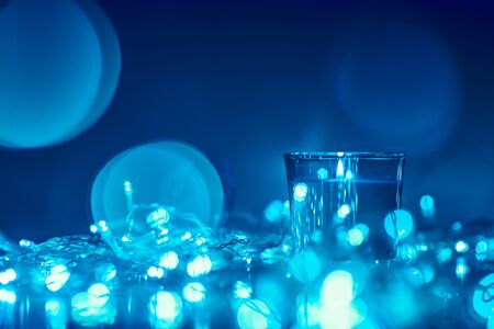 Silhouette of burning candle with golden blurred lights on dark background, blue toned photoの写真素材