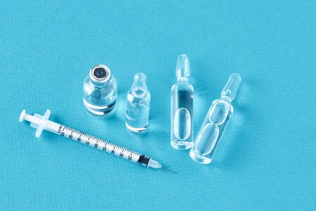 Syringes and medicine bottles with medication on blue backgroundの写真素材