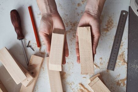 Carpenter hands holding wooden planks over table in workshop. Concept of DIY woodwork and furniture...
