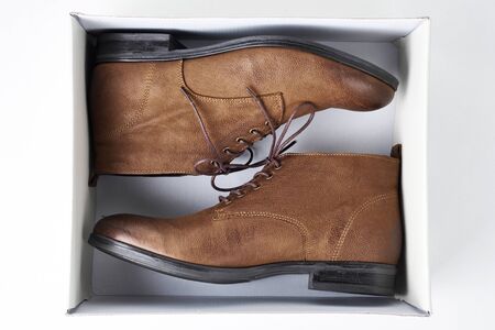 Pair of new brown leather womens boots in open box on white background, top view