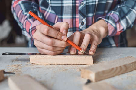 Carpenter hands taking measurement with pencil of wooden plank. Concept of DIY woodwork and...