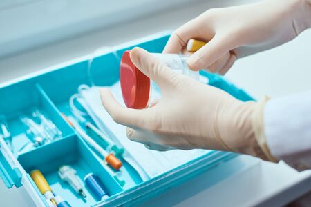 Hands in medical gloves take a test cup from medicine box. Healthcare and medicine concept. First...