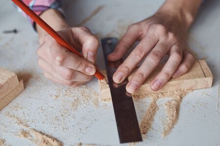 Carpenter hands taking measurement with pencil of wooden plank. Concept of DIY woodwork and furniture makingの写真素材