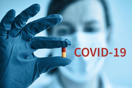 Woman with protective mask hold medical pill in hand. Coronavirus problem and covid-19 protection...
