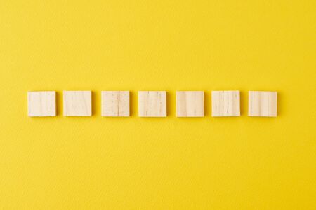 Wooden blocks in row on yellow background, top viewの写真素材