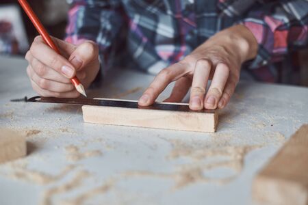 Carpenter hands taking measurement with pencil of wooden plank. Concept of DIY woodwork and furniture makingの写真素材