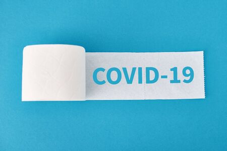 Buying panic due to coronavirus. Toilet paper roll on blue background and inscription covid-19の写真素材