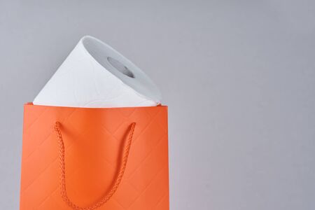 Toilet paper roll in shopping bag as gift on gray backgroundの写真素材