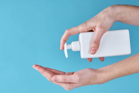 Concept of COVID-19 outbreak health protection with antiseptic. Woman wash hands using sanitizer or antiseptic gel as prevention measure for coronavirus on blue backgroundの写真素材