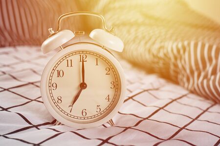 White vintage alarm clock and pillows in bed. Wale up and morning concept