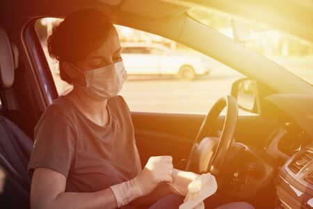 Woman in protective mask and medicine gloves driving car. Protection from virus epidemic and infectionの写真素材