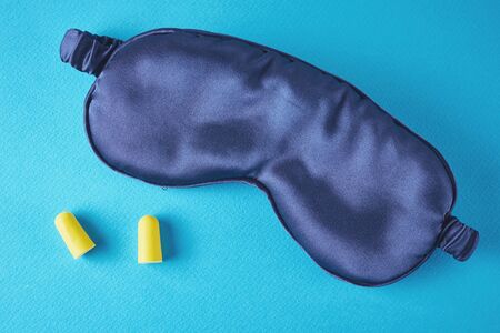 Insomnia and sleeping problem concept.Sleeping mask and ear plugs on blue background, top viewの写真素材