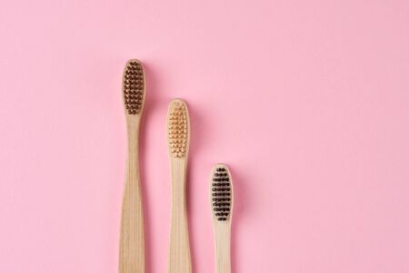 Three bamboo toothbrushes on pink background, top view flat lay. Zero waste and eco friendly concept