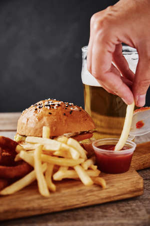 Different types of fastfood and snacks and glass of beer on table. Unhealthy and junk food.
