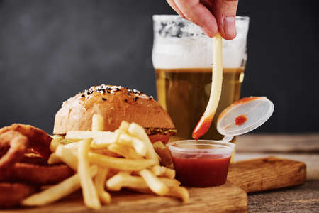 Different types of fastfood and snacks and glass of beer on table. Unhealthy and junk food.の写真素材
