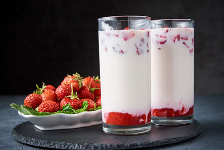 Strawberry milk smoothie in glass and fresh berries on dark backgroundの写真素材