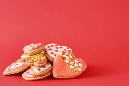 Decorated with icing and glazed heart shape cookies on red background. Valentines Day food conceptの写真素材
