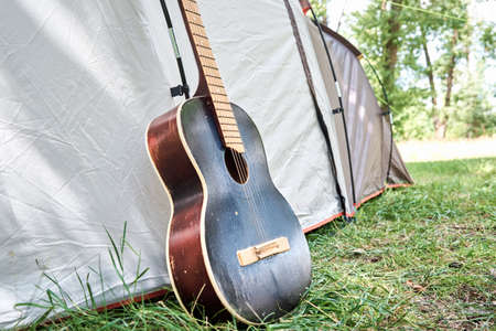 Acoustic guitar near a camping tent in a forestの写真素材