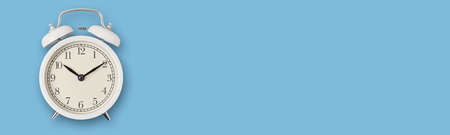 White vintage alarm clock on blue background, long banner. Urgency, deadline and running out of time...