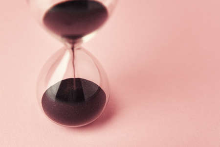 Hourglass on pink background, close up. Urgency and running out of time conceptの写真素材