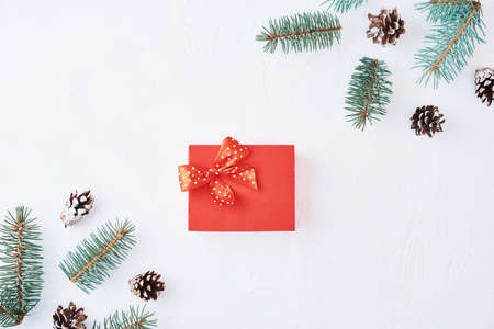 Christmas composition with copy space. Gift box decorated with fir tree branches and pine cones on white backgroundの写真素材