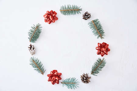 Christmas composition. Wreath made of fir tree branches and festive pine cones on white background,...
