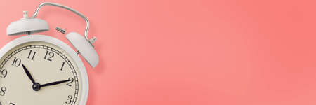 White vintage alarm clock on pink background, long banner. Urgency, deadline and running out of time conceptの写真素材